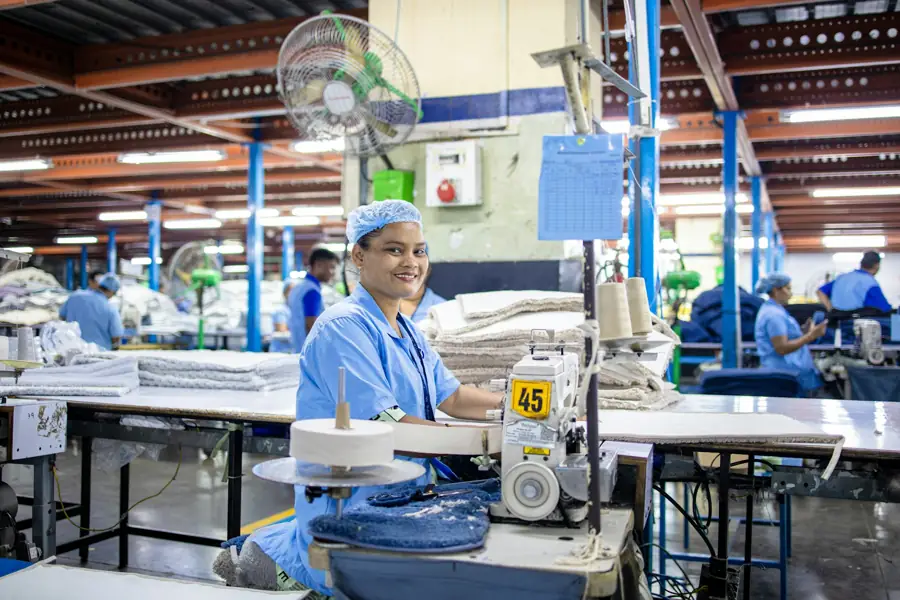 Una trabajadora sonríe frente a su máquina de coser en un taller textil