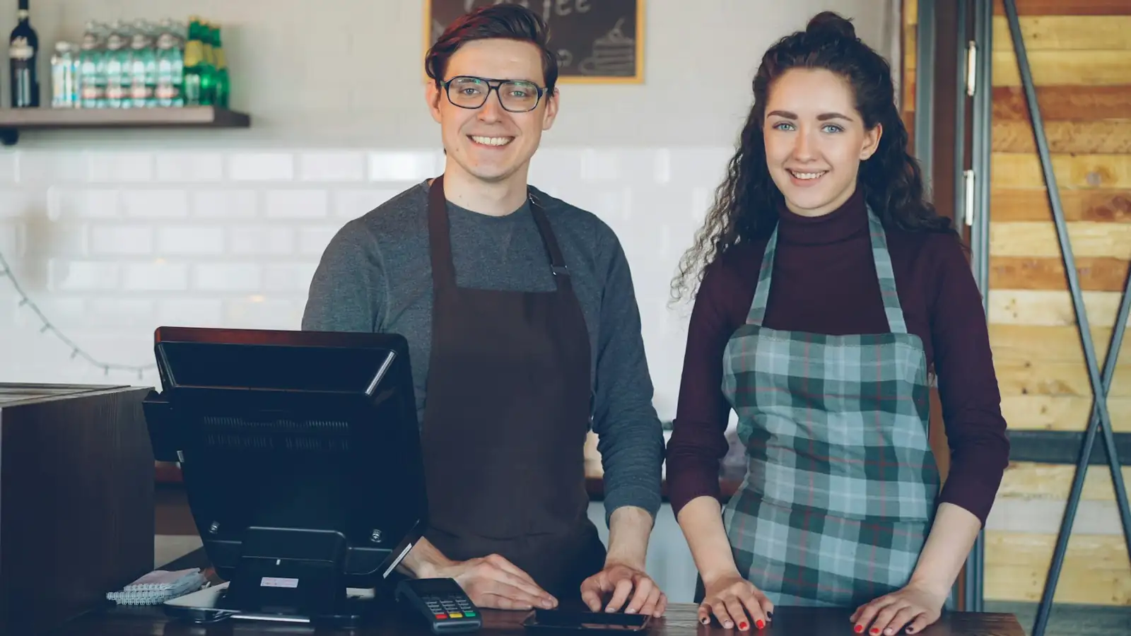 Dos empleados de una cafetería sonríen detrás del mostrador